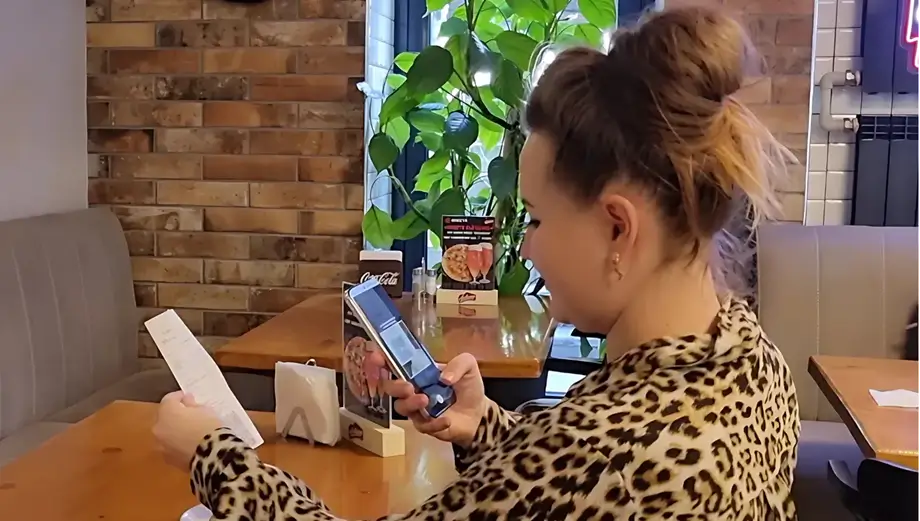 Сканирование телефоном QR-кода на чеке Девушка сканирует телефоном QR-код на чеке